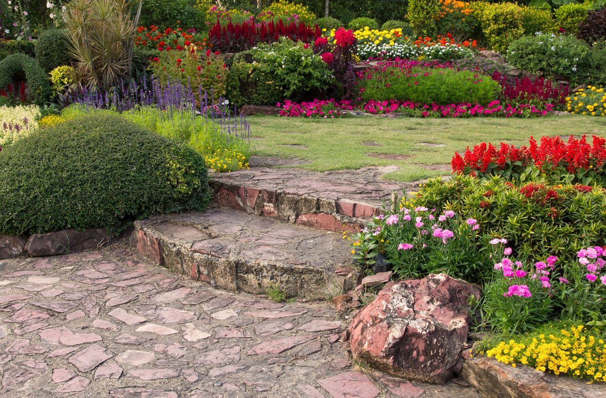 Gartenanlage mit Steinweg und bunten Blumenbeeten